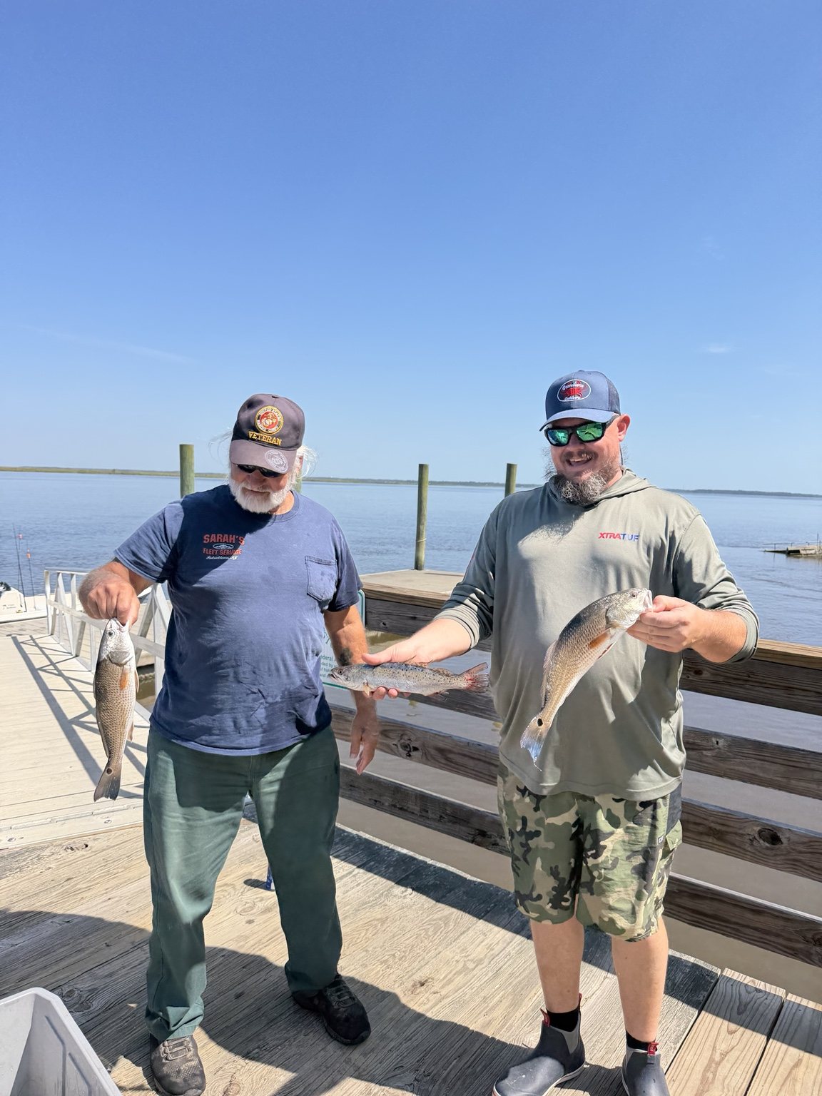 Two anglers showing off redfish and trout
