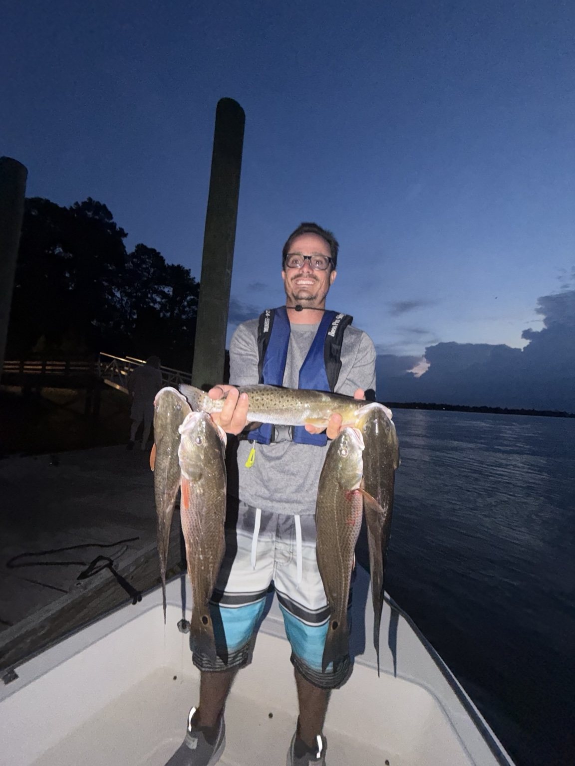 Angler holding a nighttime trout and redfish catch